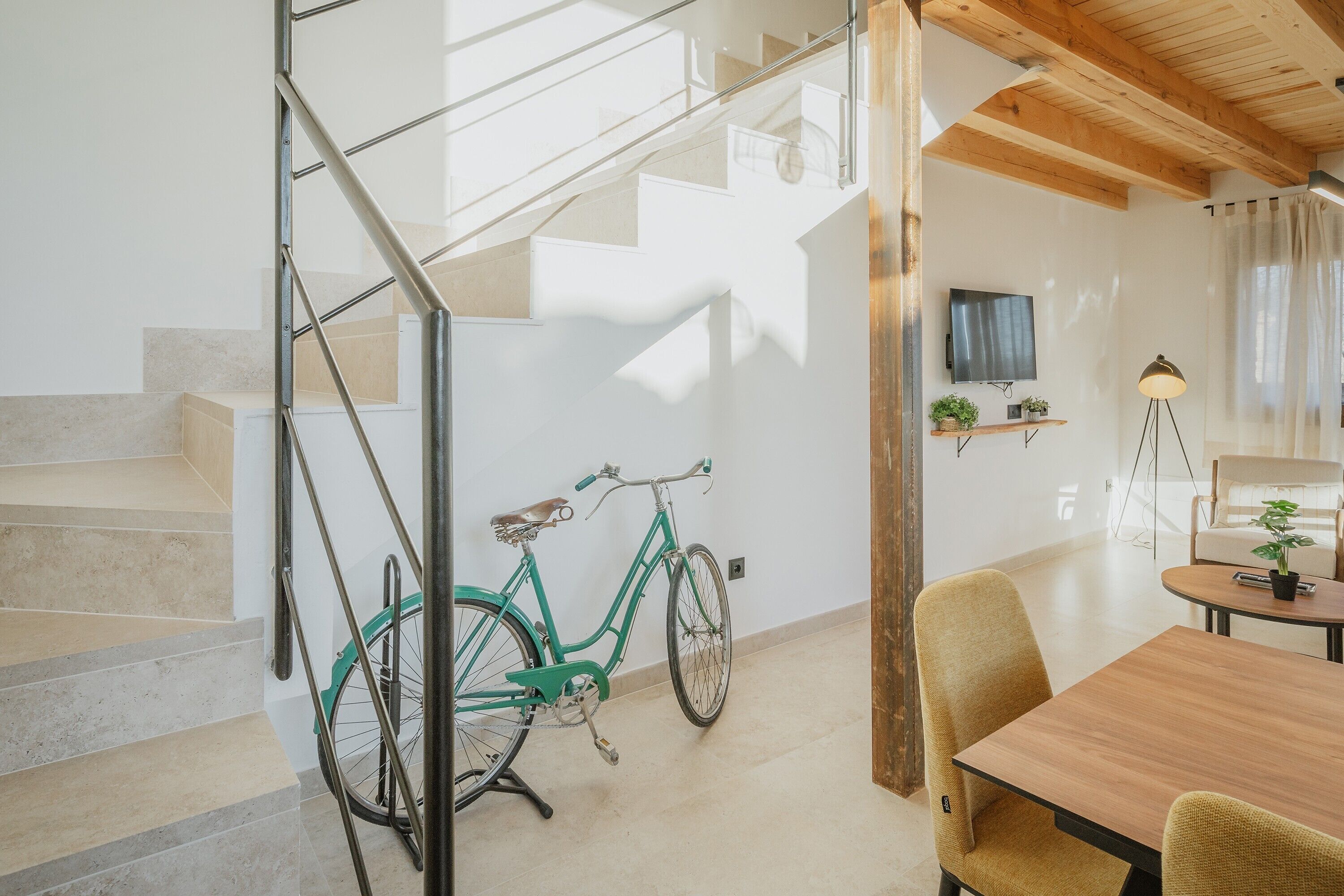 Eine Treppe mit einem grünen Fahrrad, einem Holztisch und einem Fernseher an der Wand.