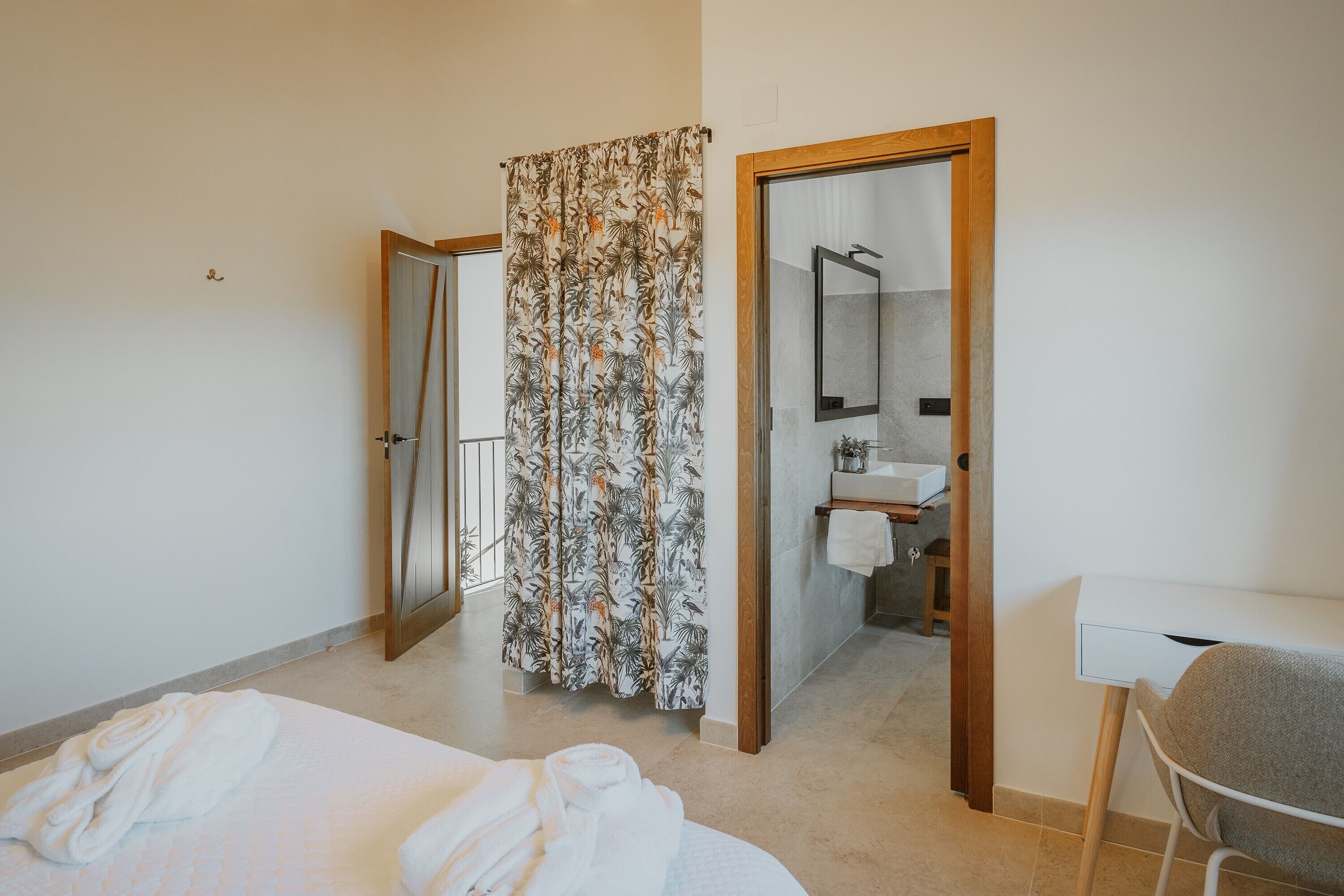 Ein Schlafzimmer mit Bett, Schreibtisch, Dusche und einem Badezimmer mit Spiegel.