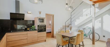 Una cocina moderna con comedor, armarios de madera y una escalera.