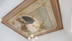 Eine Decke mit einem dekorativen Fresko, einer Chandelier und einem gerahmten Spiegel.