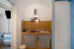 A compact kitchen with a built-in stove, a sink, and a ventilation hood.