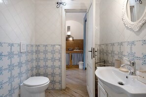 A bathroom with a toilet, sink, mirror, and patterned tiles.