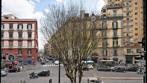 Vista de la calle con edificios, vehículos y un árbol.