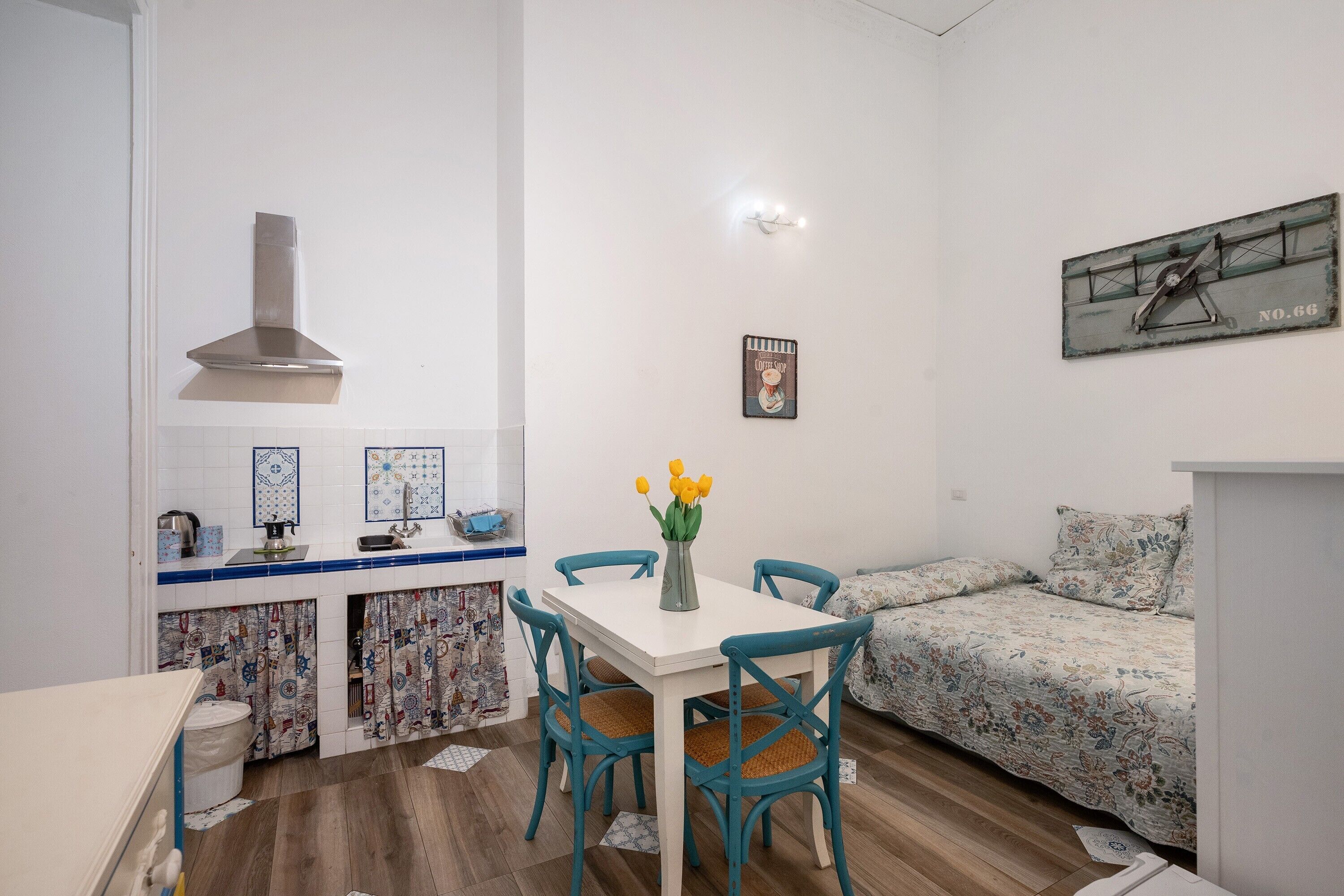 Un espace de vie compact comprenant un coin cuisine, une table à manger avec des chaises, un canapé et un élément décoratif mural.