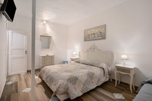 A bedroom with a bed, bedside tables, a mirror, and a wall-mounted artwork.
