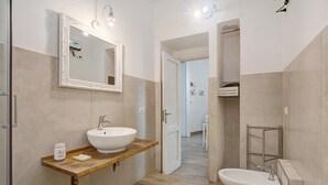 A bathroom with a large mirror, two sinks, a vanity, and a shower area.