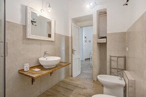 Een badkamer met een grote spiegel, twee wasbakken, een wastafelmeubel en een douchehoek.
