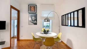 A dining area with a round table, yellow chairs, a vase with flowers, and artwork on the walls.