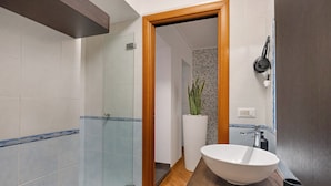 A modern bathroom with a glass shower enclosure, a white sink, and a wooden vanity.