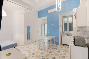 Una habitación con cama, una mesa de comedor con sillas, kitchenette y un baño.