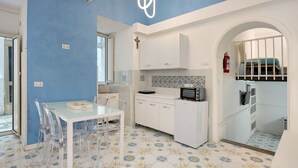 Une cuisine moderne avec des meubles blancs, une table à manger en verre et un sol carrelé à motifs.