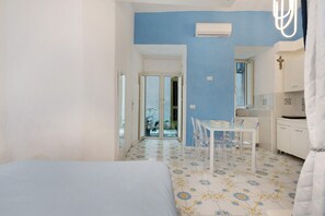Un dormitorio con cama, una zona de comedor con mesa y sillas, y una cocina con armarios y lavabo.