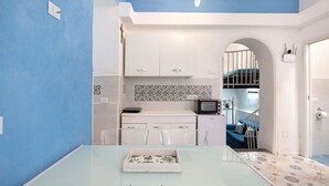 Une cuisine moderne avec des meubles blancs, une table en verre et un revêtement mural décoratif.