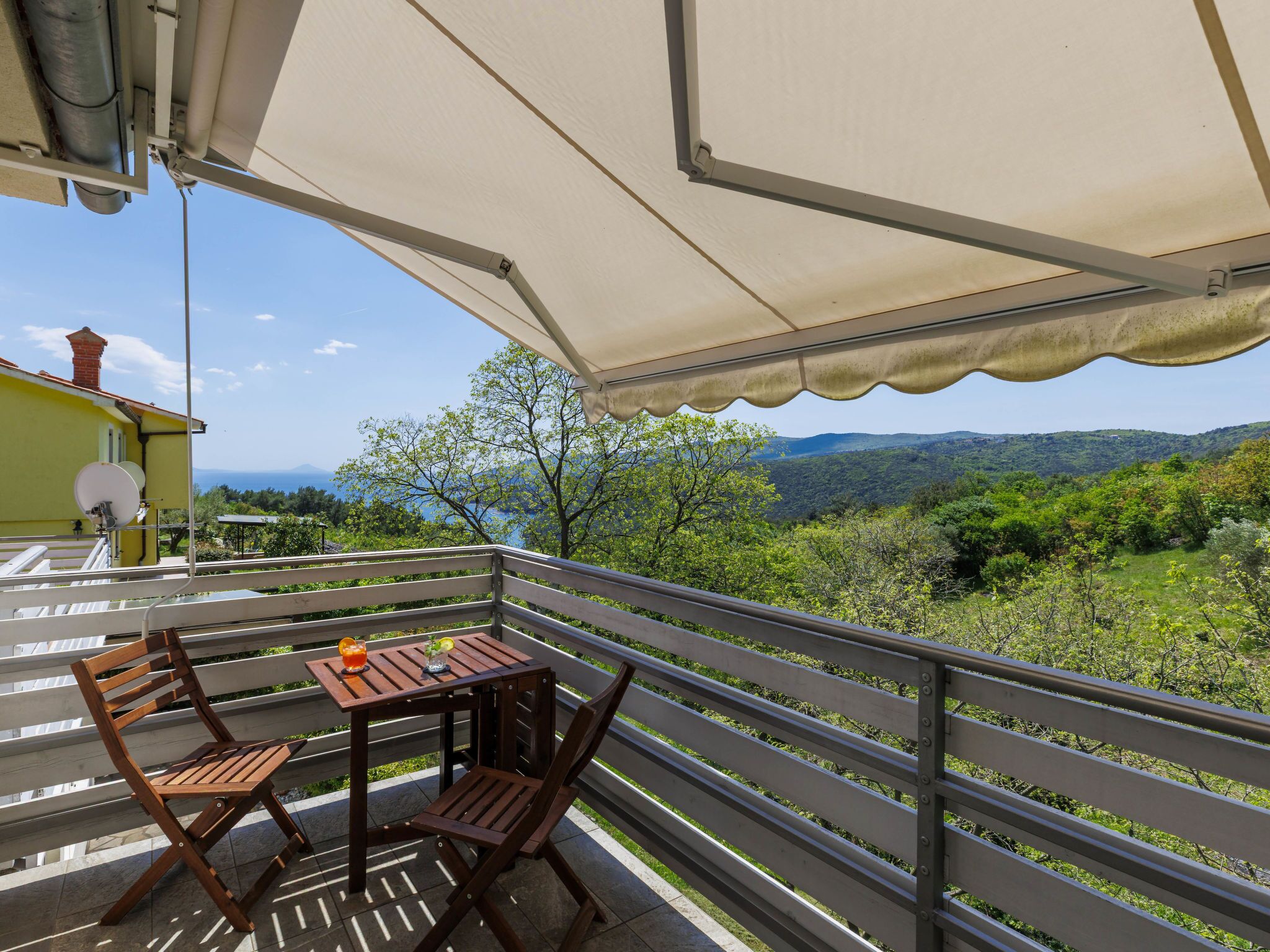 Een balkon met een tafel en stoelen, met uitzicht op een bergachtig landschap.