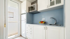 A kitchen with white cabinets, a microwave, a sink, and a bowl of fruit. - Apartment 'Sf1' with Wi-Fi and Air Conditioning (L'Ametlla de Mar)