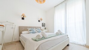 A neatly arranged bedroom with a bed, bedside lamps, a bedside table, and a window with curtains. - Apartment 'Sf1' with Wi-Fi and Air Conditioning (L'Ametlla de Mar)
