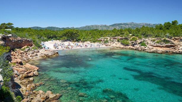 A coastal beach with clear turquoise water, rocky terrain, and a sandy area with umbrellas. - Apartment 'Sf1' with Wi-Fi and Air Conditioning (L'Ametlla de Mar)