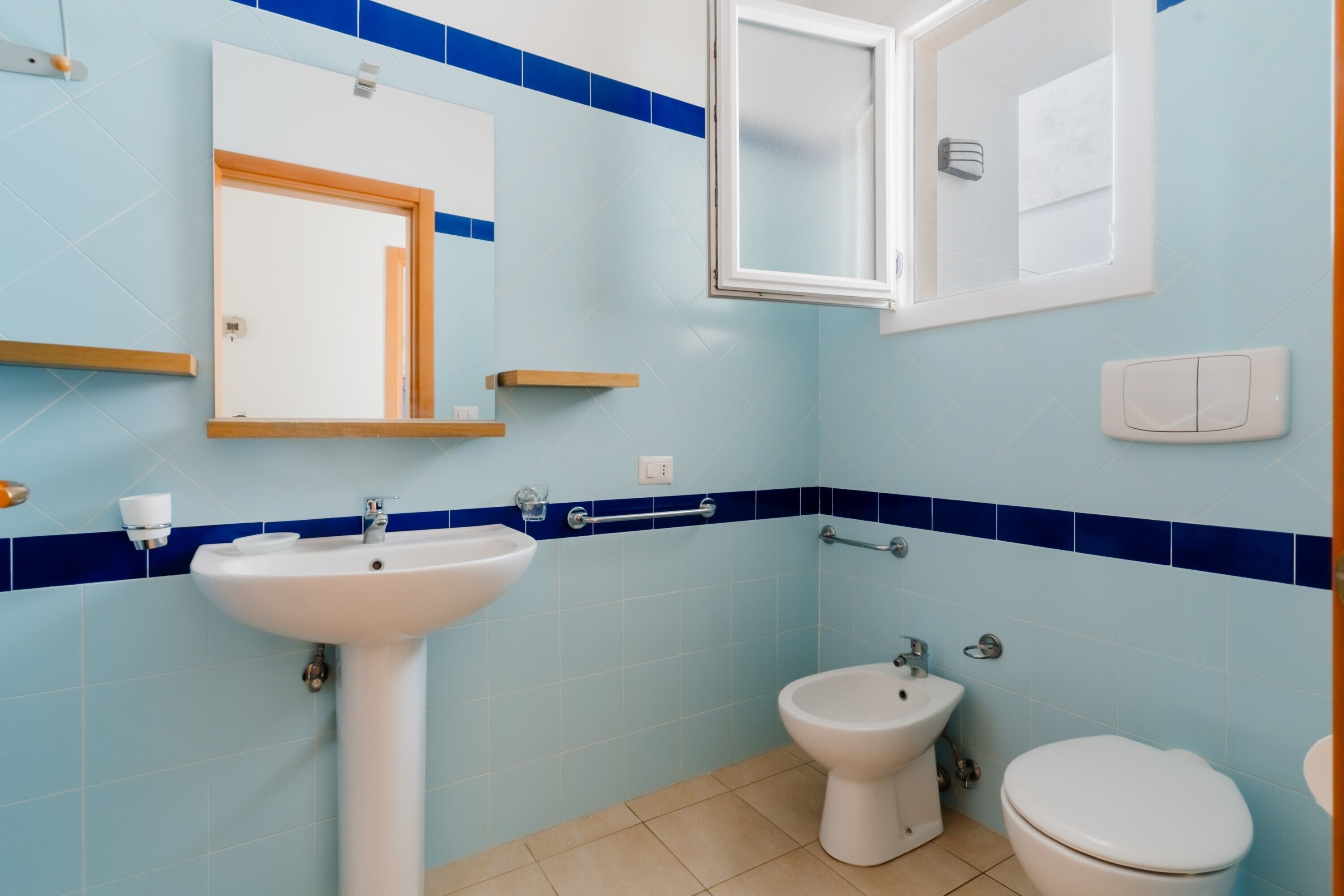 Une salle de bain équipée d’un lavabo, d’un bidet, de toilettes, d’un miroir et d’un porte-serviettes.