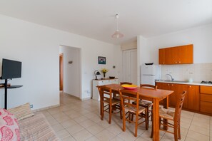Una cucina moderna con mobili in legno, un tavolo da pranzo con sedie, una TV e un'isola con lavello e piano cottura.