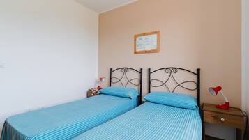 Ein Schlafzimmer mit zwei Betten, einem Nachttisch, einer Lampe und einem gerahmten Bild an der Wand.