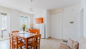 Een lichte, open woonkamer met een eethoek, keuken en een bank.