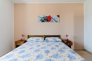 A bedroom with a bed, two bedside tables with lamps, a wall-mounted artwork, and a patterned bedspread. - Apartment 'Residence Punta Pizzo - Mare' with Air Conditioning (marina di mancaversa)