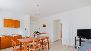 Una cocina moderna con armarios de madera, una mesa de comedor con sillas, una pequeña isla y un televisor sobre un mueble.