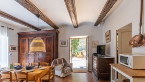 Un espace repas avec des meubles en bois, un luminaire suspendu en fibres tressées et une vue sur une terrasse extérieure.