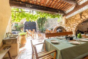 Un área de comedor al aire libre con paredes de piedra, muebles de madera y un ambiente rústico.