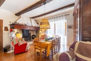 Un comedor con mesa de madera, sillas, chimenea y lámpara colgante.