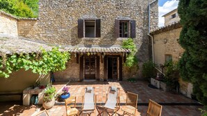 Un bâtiment en pierre doté d’une cour, d’un espace extérieur aménagé pour s’asseoir et d’un petit jardin.