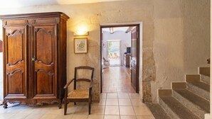 Un couloir avec une armoire en bois, une chaise et un escalier menant à une autre pièce.