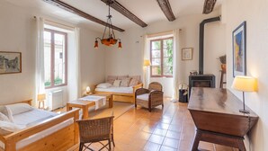 Une pièce chaleureuse avec un lit, une table en bois, des chaises en osier et une cheminée.