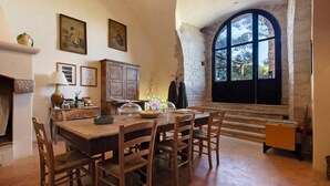 A dining area with a wooden table and chairs, a fireplace, and a large arched window. - Apartment 'Cerere' with Shared Terrace, Wi-Fi and Air Conditioning (Bisceglie)