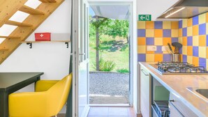 A kitchen with a gas stove, a sink, a wooden ceiling, and a view of the outdoors.