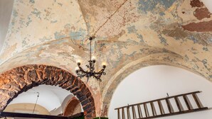Une pièce dotée d’une arche en pierre, d’un lustre et d’une poutre en bois au mur.