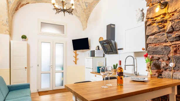 Une cuisine moderne avec un mur en pierre, une table à manger en bois et un téléviseur fixé au-dessus.