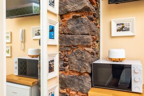 Une cuisine équipée d’un four à micro-ondes, d’un téléphone et de tableaux accrochés au mur.