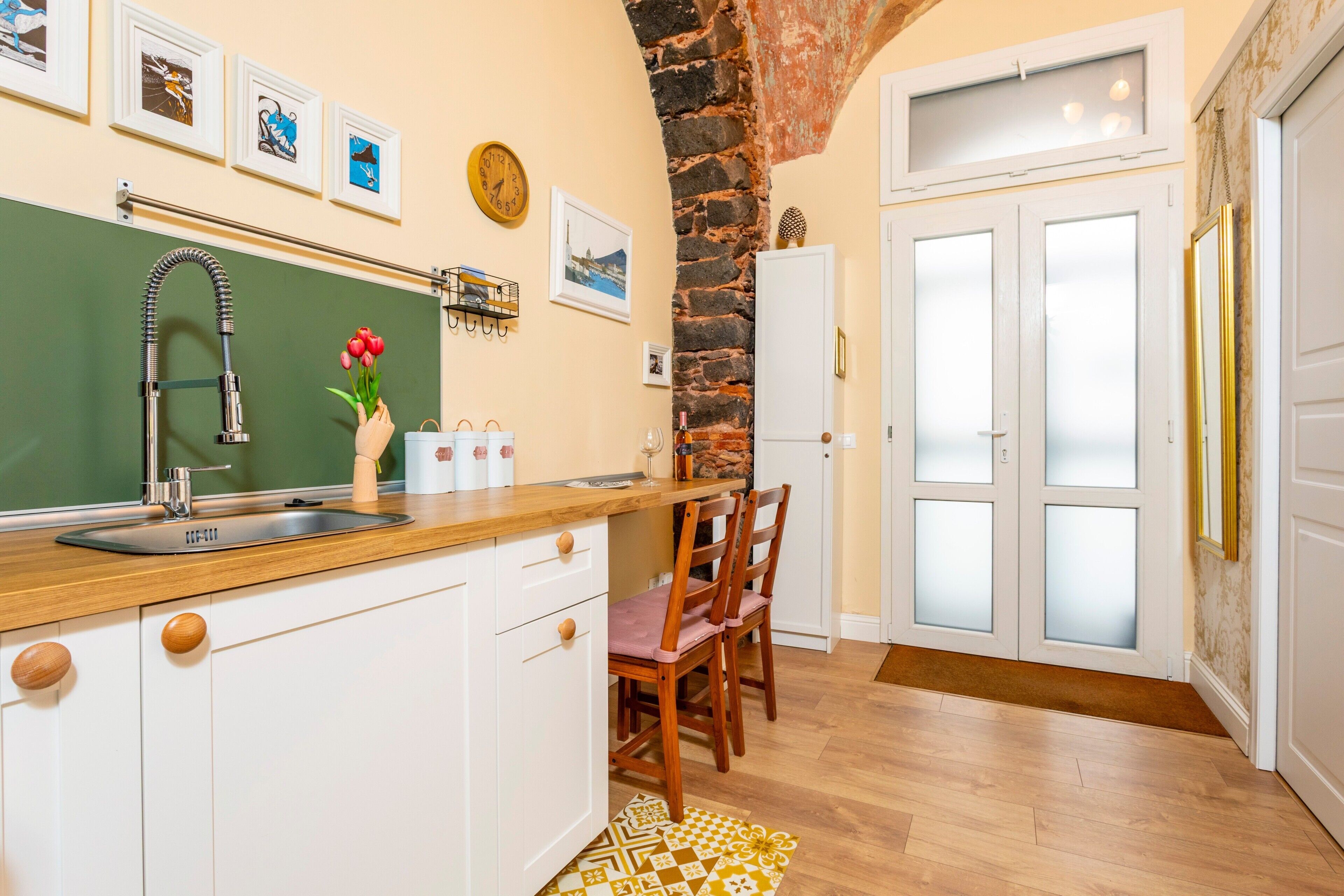 Eine Küche mit Holzausziehtisch, weißen Schränken, einer Steinwand und einem Essbereich mit Stühlen.