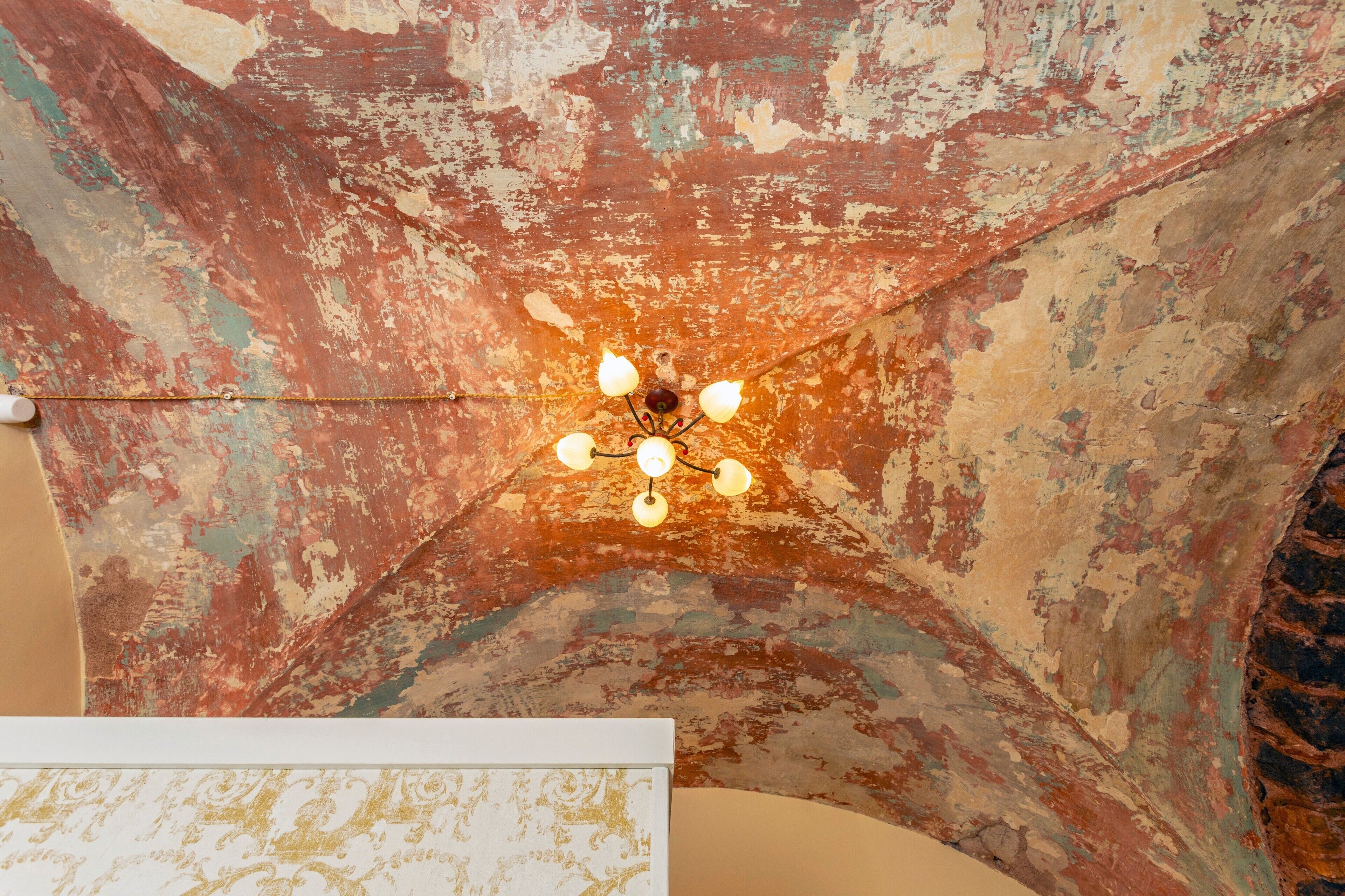 Eine Decke mit abblätternder Farbe und einer Kandelaber.