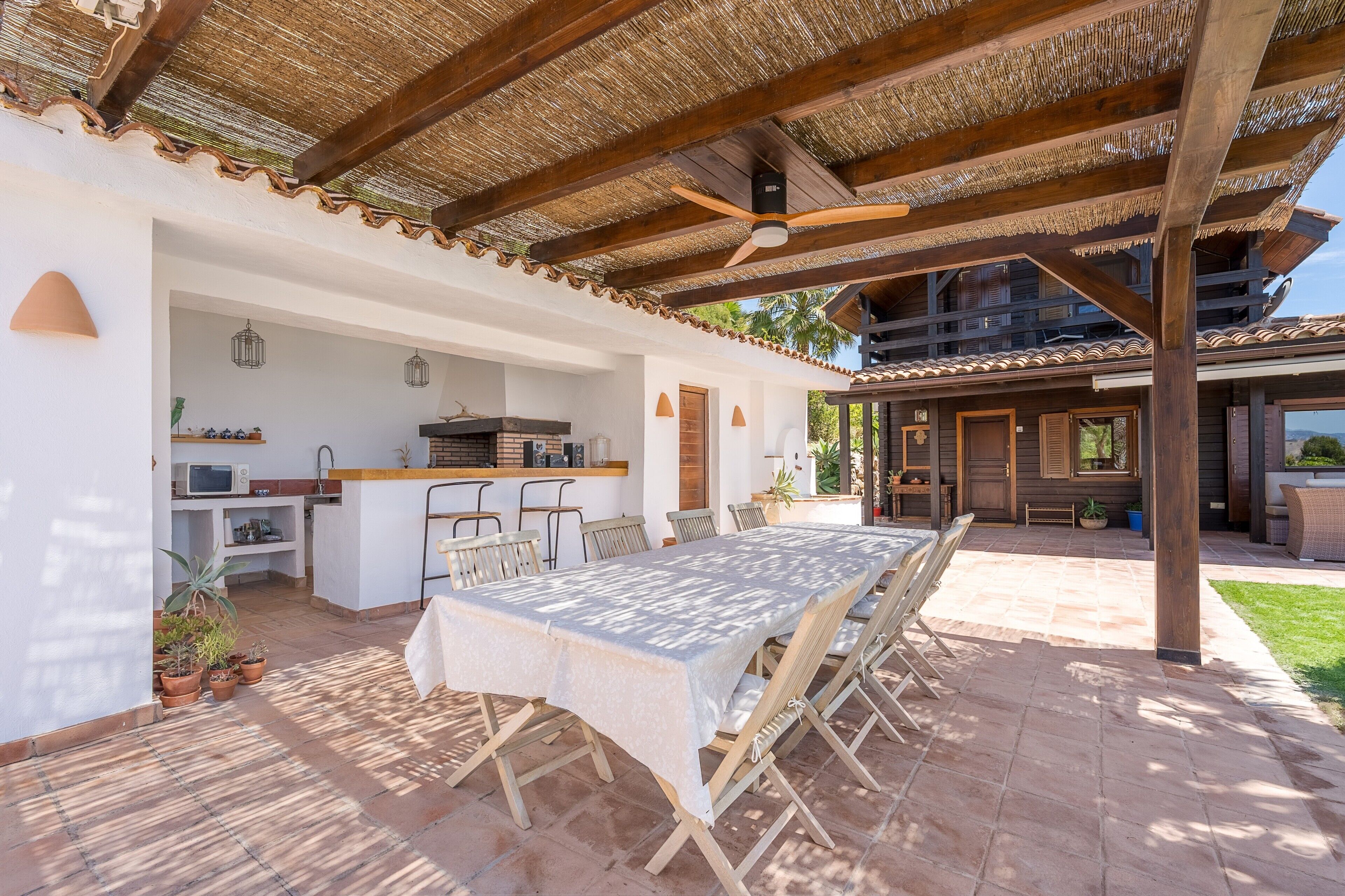 A covered outdoor dining area with a table, chairs, and a ceiling fan.