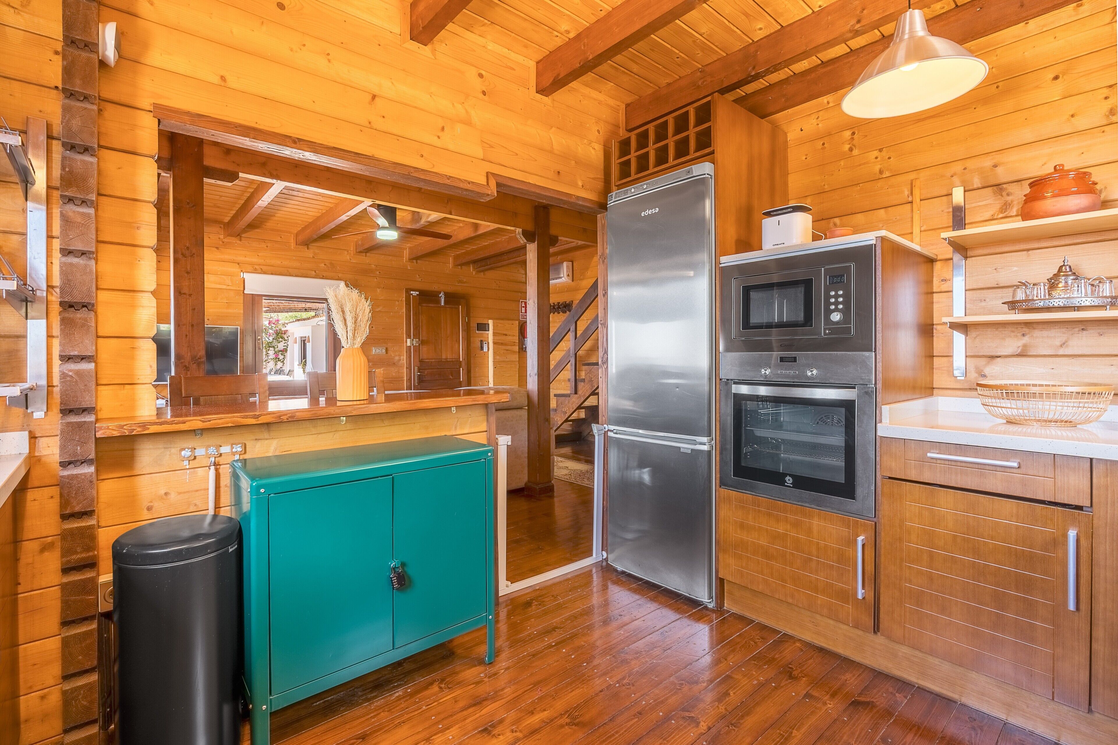 Un interior de madera con un refrigerador de acero inoxidable, un microondas y un horno.