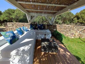 An outdoor seating area with a pergola, stone wall, and lush greenery. - Red Apartment Calma Natural (Los Caños de Meca)