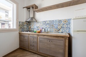 Una cocina con salpicadero de azulejos, armarios de madera, una campana extractora de acero inoxidable y un refrigerador blanco.