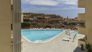 A swimming pool with lounge chairs, a view of buildings, and a clear sky.