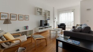 A modern living room with a TV, sofa, coffee table, and bookshelves.