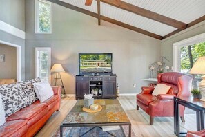 A living room with a red leather sofa, a glass coffee table, and a dark wooden cabinet.