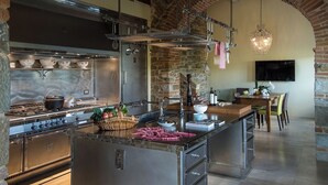 A modern kitchen with a central island, stainless steel appliances, and a stone archway. - Villa Piandolce - Radda In Chianti (SI)