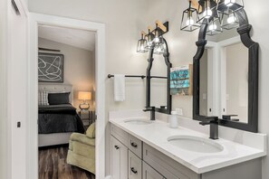 Un baño moderno con lavamanos doble, un espejo grande y una lámpara de pared original.