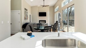 Une cuisine moderne dotée d’un grand îlot central, d’un évier en acier inoxydable et de luminaires suspendus.